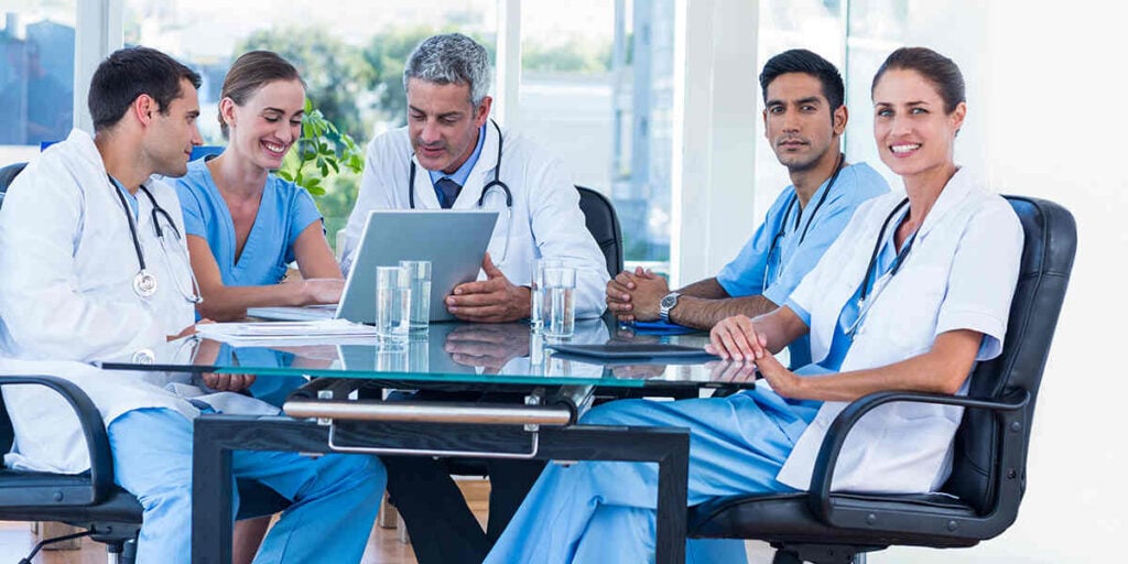 Healthcare professionals collaborating in a modern office setting, discussing medical practice startup services, emphasizing teamwork and operational efficiency.